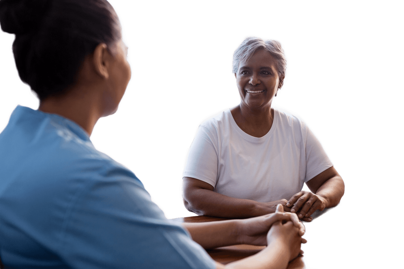 A nurse holding hands with a senior woman at a table