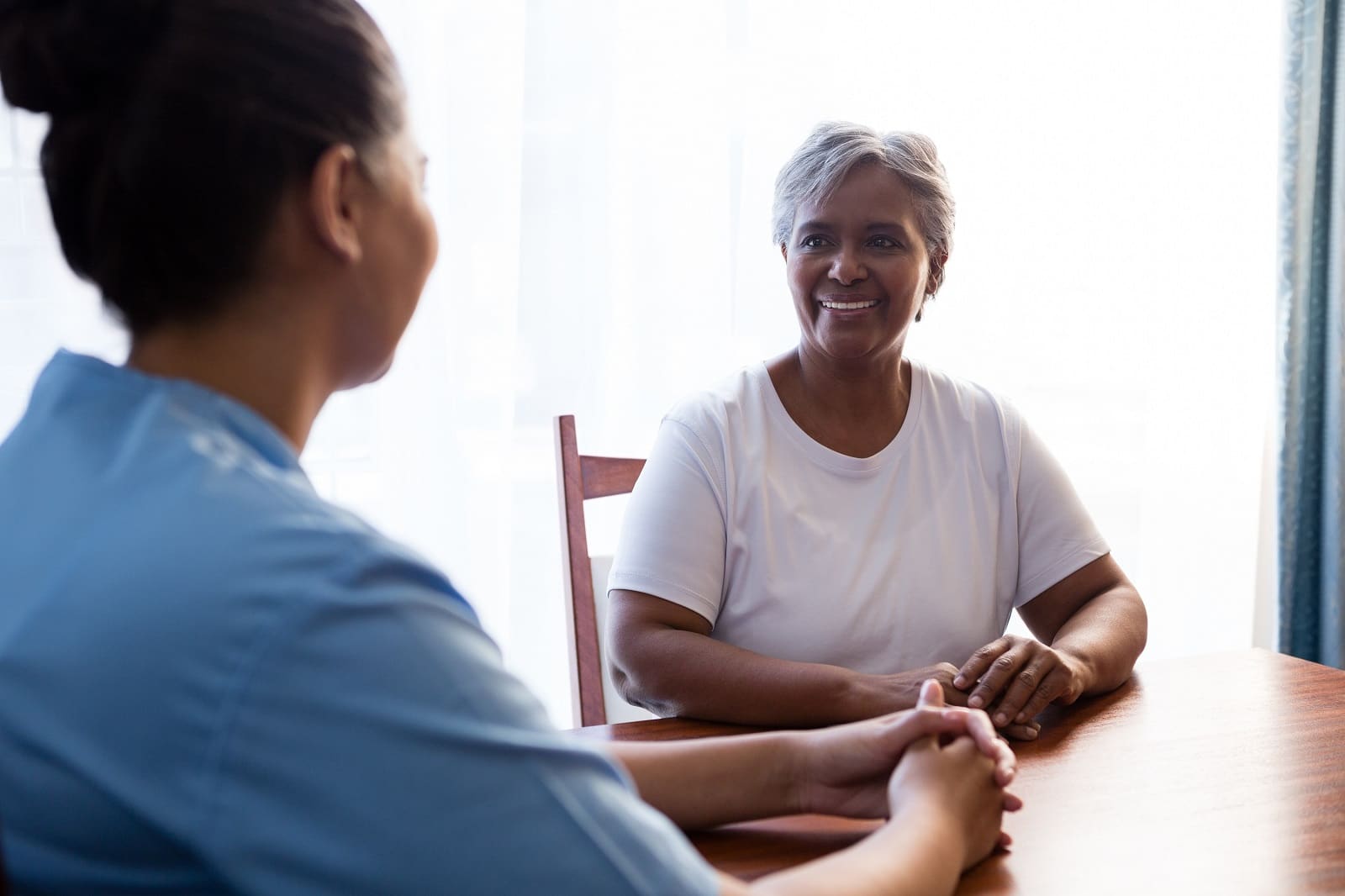 A nurse interacting with a senior woman at a table